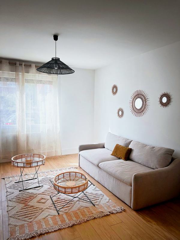 Living room with a large sofa, rattan coffee tables and sunburst mirrors