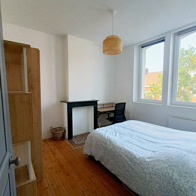 Bedroom with a bed, desk and a fireplace between two large windows