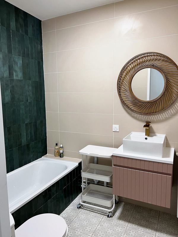 Bathroom with a bathtub, green tiles, a washbasin and a rattan mirror