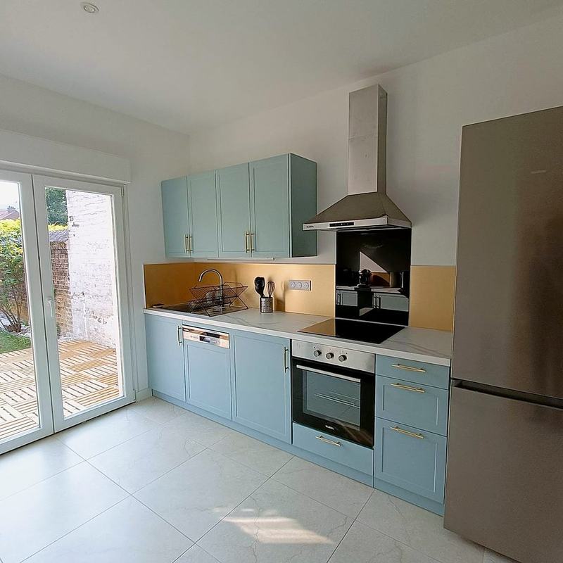 Fitted kitchen with oven, hob and fridge-freezer opening onto the garden