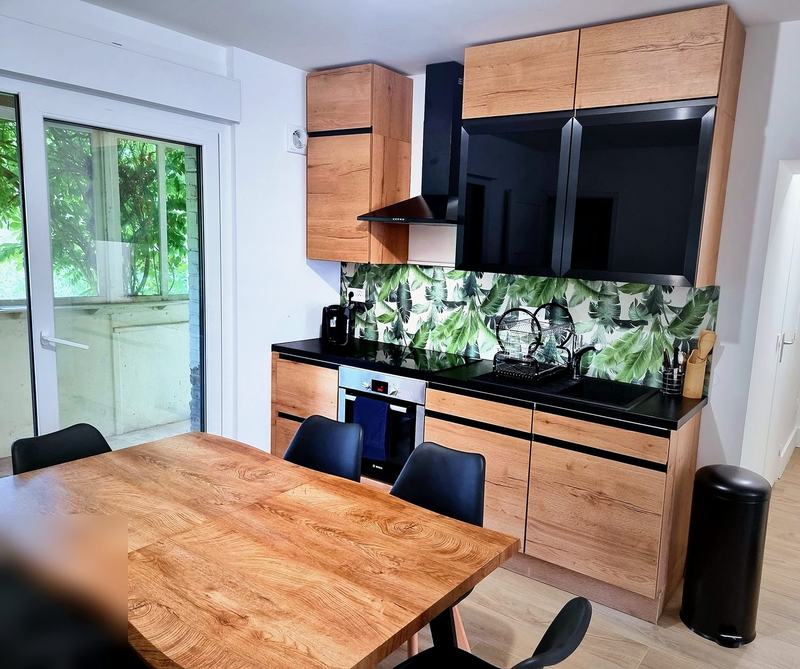 Fitted kitchen with oven, hob, extractor hood and a large wooden dining table