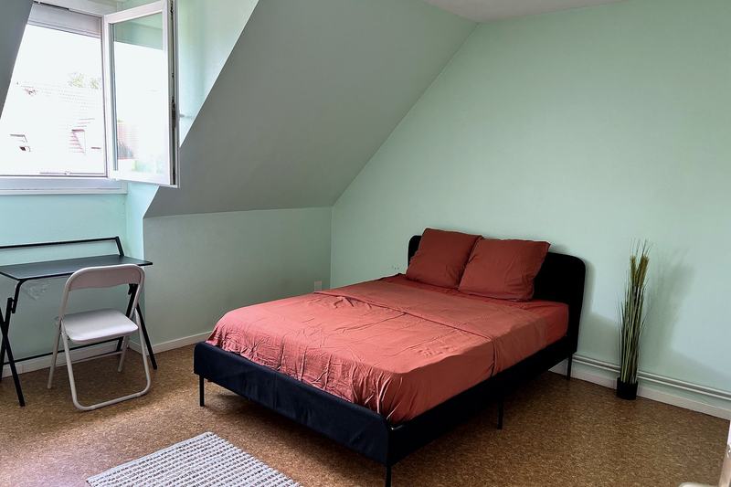 Bedroom under the eaves with a bed, desk and chair