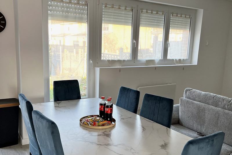 Living and dining area with a marble-effect table, blue chairs and large windows over the garden