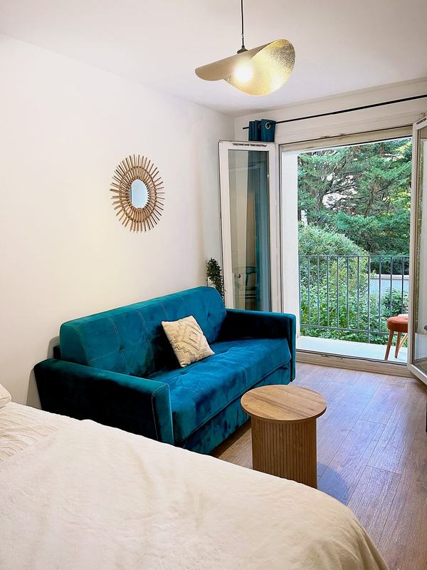 Teal sofa facing the French window opening onto the balcony