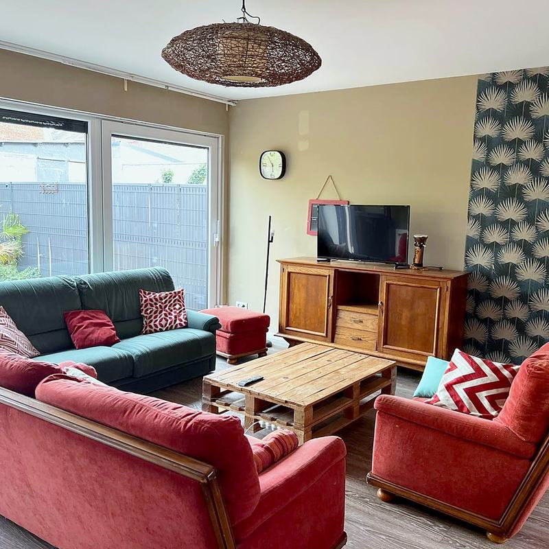 Living room with sofas, an armchair and a TV opening onto the garden