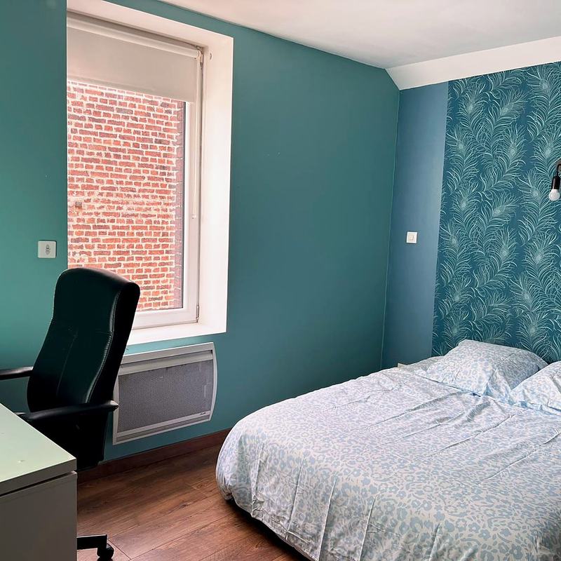 Bedroom with a bed, desk and a teal accent wall