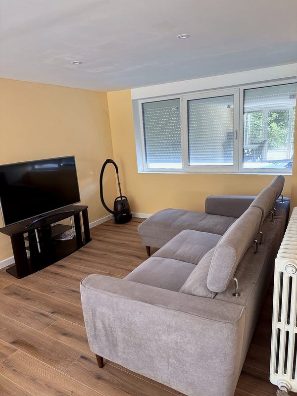 Living room with a large corner sofa, a TV and a radiator