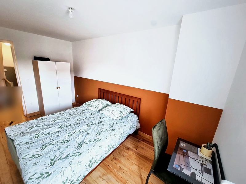 Bedroom with a bed, wardrobe, desk and a terracotta accent wall
