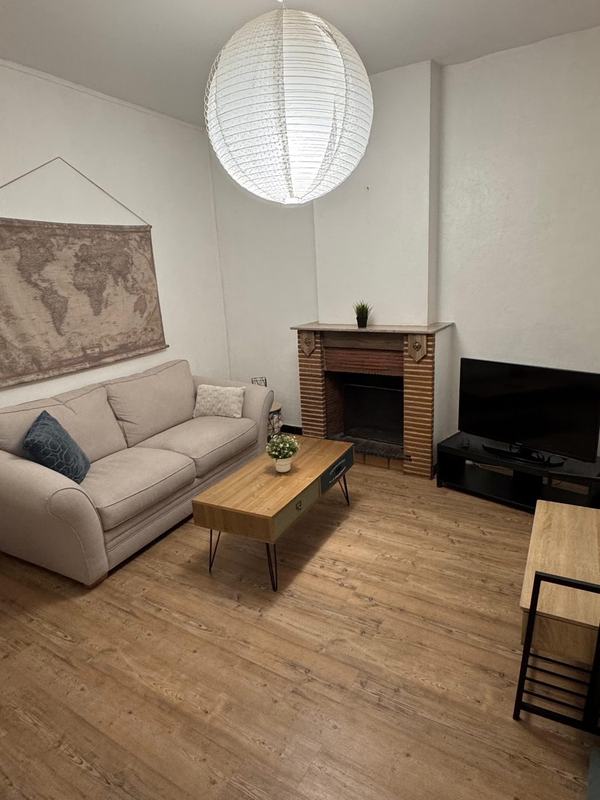 Living room with a sofa, fireplace and TV in a three-bedroom house in Valenciennes