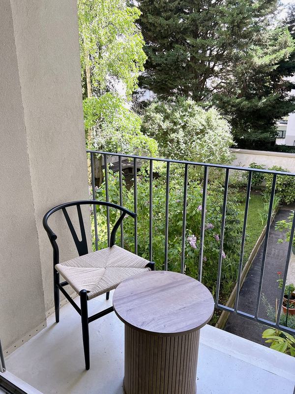 Small balcony with a chair and side table above the garden