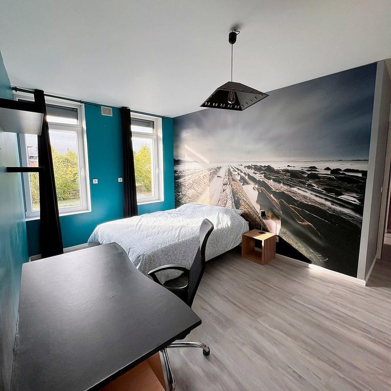 Bedroom with a bed, desk and a large seascape mural