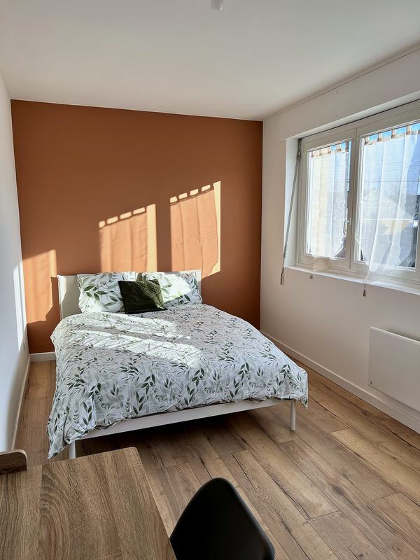 Bright bedroom with a double bed, a terracotta wall and a desk